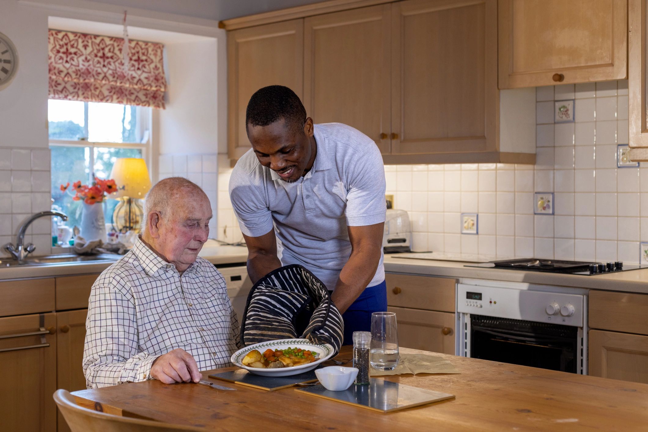 Serving a hot meal to a senior man at home