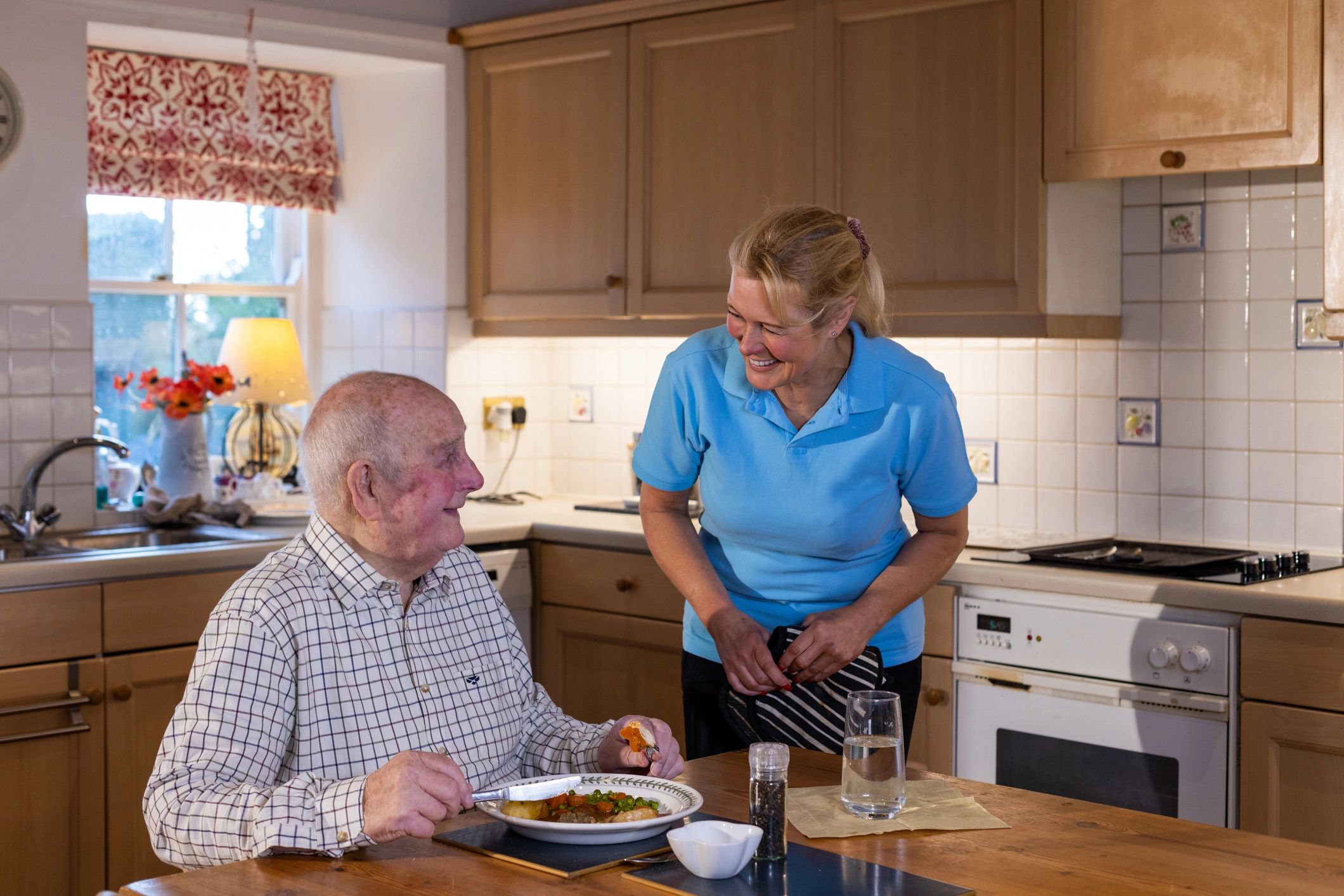 Caregiver serving dinner to a senior man at home