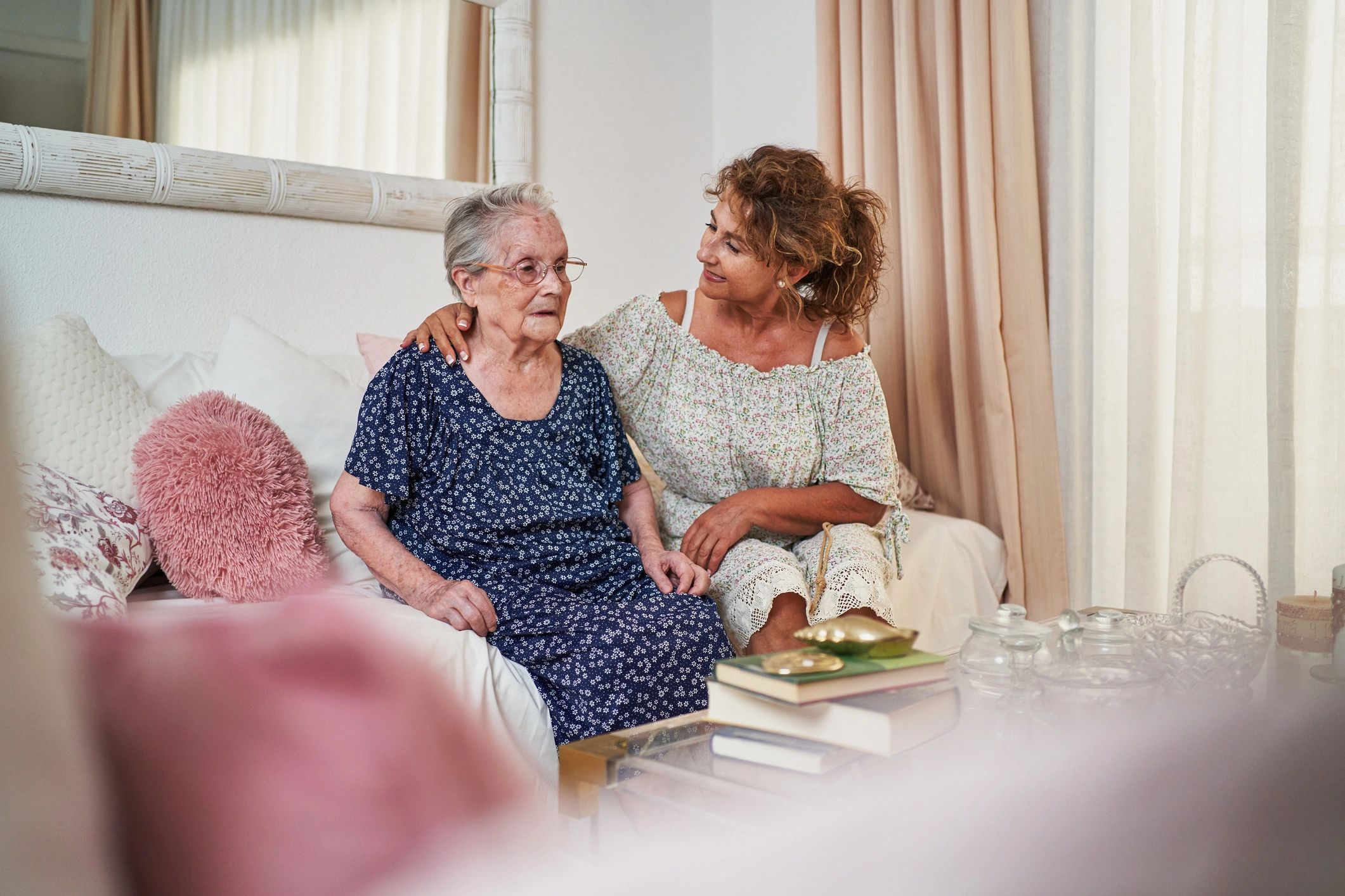 Daughter comforting elderly mother sitting on sofa at home